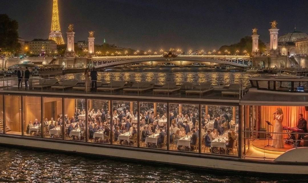 Dinner-Kreuzfahrt auf der Seine in Paris mit Live-Musik. Panoramaboot mit großen Glasfenstern, das Gäste beherbergt, die von einer Sängerin und einem Musiker live unterhalten werden, mit nächtlichem Blick auf den Eiffelturm und die beleuchteten Brücken im Hintergrund.