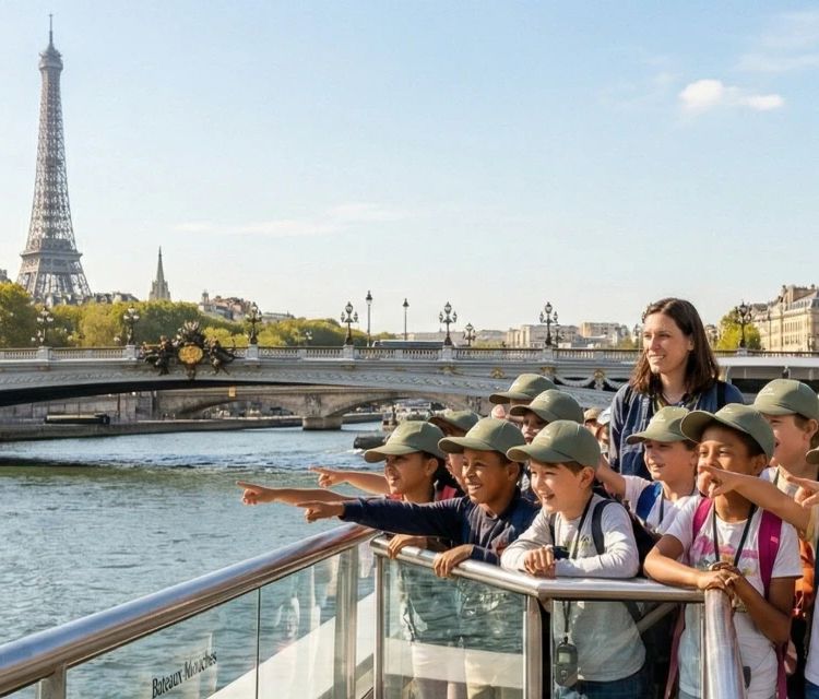 Groep leerlingen op schoolreis en hun leraren bewonderen de Eiffeltoren en de Pont Alexandre III vanaf het dek van een rondvaartboot op de Seine in Parijs.